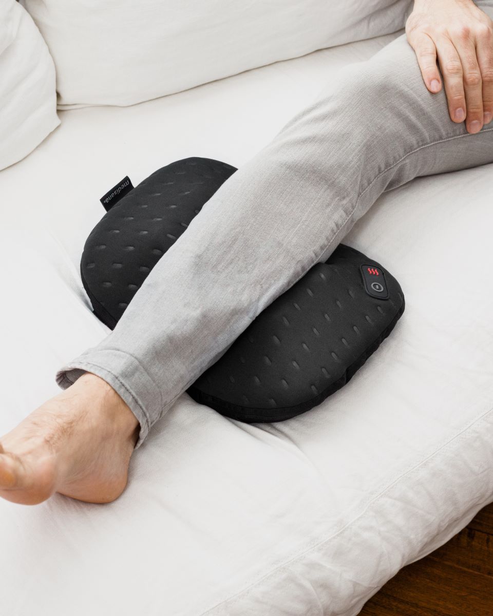 Eine Person massiert mit einem Medisana Massagekissen die Waden für gezielte Muskelentspannung.